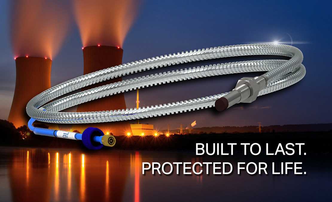 An 8 millimeter PRO Line armored proximity probe extension cable in front of a black and white photograph of an off-shore oil rig